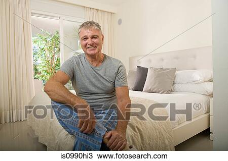 Stock Image - Senior man sitting on bed. Fotosearch