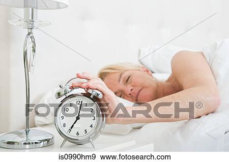 Woman in bed, turning off alarm View Large Photo Image Stock Photo - Woman in bed, turning off alarm. Fotosearch