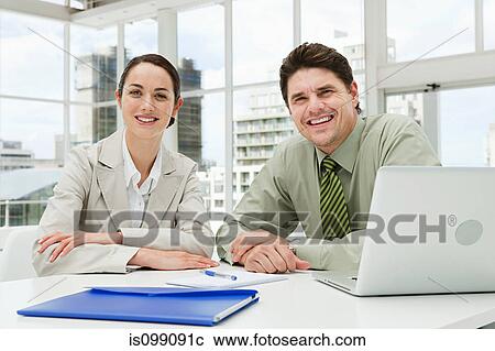 Stock Image - Businessman and businesswoman meeting in office with laptop. Fotosearch