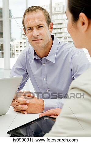 Stock Photograph - Businessman and businesswoman meeting in office. Fotosearch