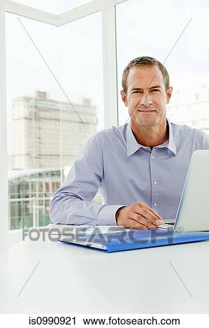 Stock Image - Businessman using laptop in office. Fotosearch