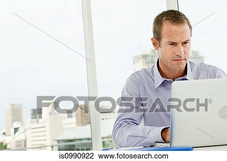 Stock Image - Businessman using laptop in office. Fotosearch