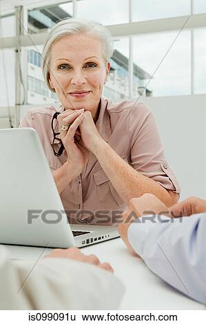 Mature businesswoman in office with laptop View Large Photo Image Stock Photograph - Mature businesswoman in office with laptop. Fotosearch