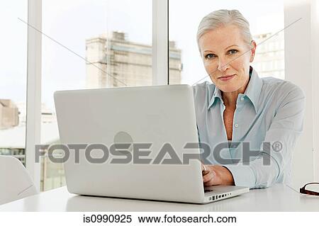Stock Photography - Mature businesswoman using laptop. Fotosearch