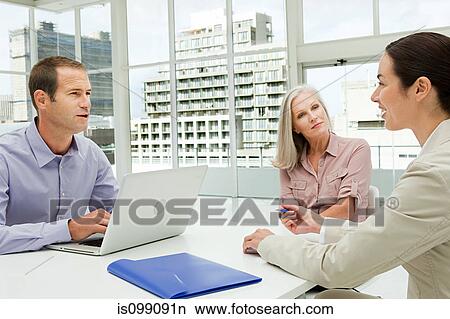 Picture - Three businesspeople meeting in office using laptop. Fotosearch