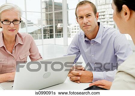 Three businesspeople meeting in office using laptop View Large Photo Image Stock Photograph - Three businesspeople meeting in office using laptop. Fotosearch