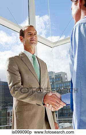 Stock Photography - Two businessmen shaking hands in office. Fotosearch
