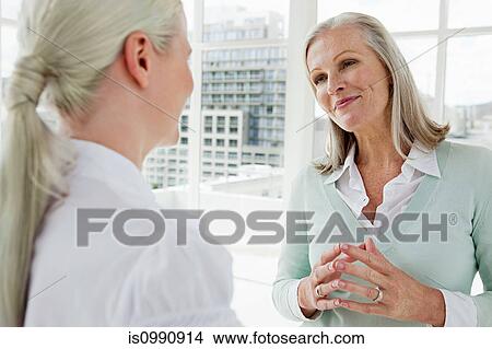 Picture - Two businesswomen talking in office. Fotosearch