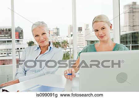 Two businesswomen using laptop in office View Large Photo Image Stock Image - Two businesswomen using laptop in office. Fotosearch