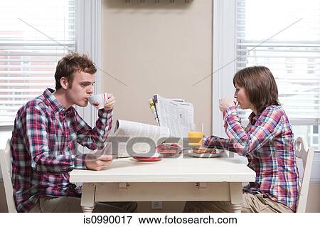 Young couple having breakfast at kitchen table View Large Photo Image Stock Photo - Young couple having breakfast at kitchen table. Fotosearch