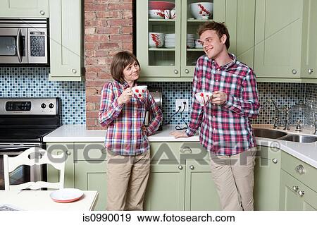 Young couple holding teacups in kitchen View Large Photo Image Stock Photo - Young couple holding teacups in kitchen. Fotosearch