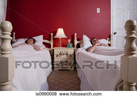 Young couple lying awake in single beds View Large Photo Image Stock Photo - Young couple lying awake in single beds. Fotosearch