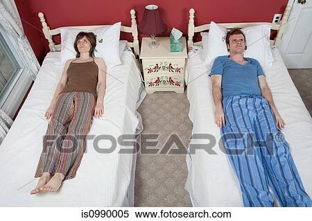 Young couple lying on single beds, ignoring each other View Large Photo Image Stock Photography - Young couple lying on single beds, ignoring each other. Fotosearch