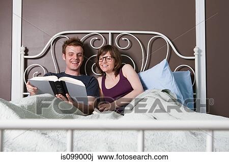 Young couple reading in bed View Large Photo Image Stock Image - Young couple reading in bed. Fotosearch