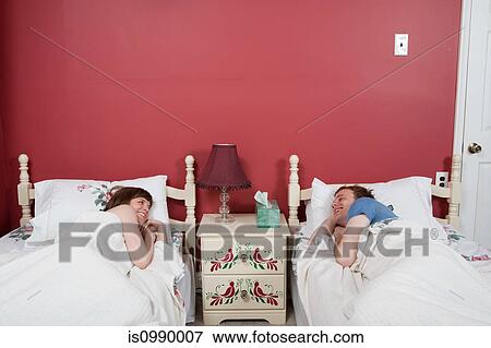 Young couple smiling at each other in single beds View Large Photo Image Stock Photo - Young couple smiling at each other in single beds. Fotosearch