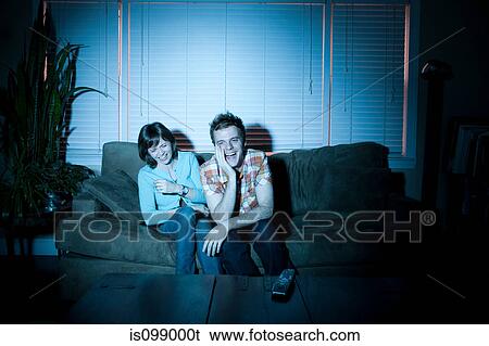 Young couple watching tv, laughing View Large Photo Image Stock Photograph - Young couple watching tv, laughing. Fotosearch