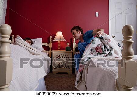 Stock Photo - Young man getting out of bed to see young woman. Fotosearch