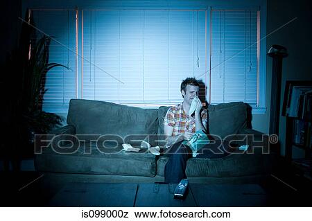 Stock Photo - Young man watching tv, crying. Fotosearch