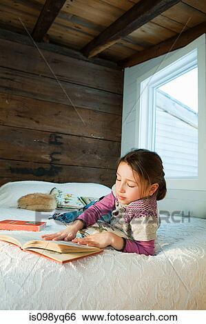 Young girl lying on bed reading book View Large Photo Image Stock Photograph - Young girl lying on bed reading book. Fotosearch