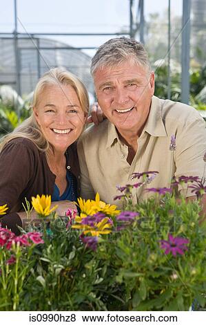 Stock Photo - Mature couple with flowers in garden centre. Fotosearch