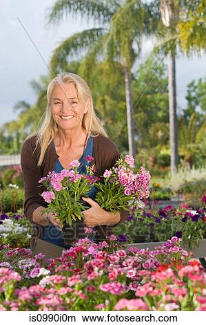 Picture - Woman with flowers at garden centre. Fotosearch