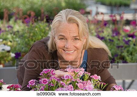 Stock Image - Woman with flowers at garden centre. Fotosearch