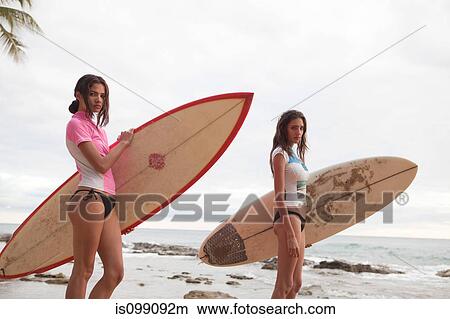 Two young women holding surfboards, portrait View Large Photo Image Picture - Two young women holding surfboards, portrait. Fotosearch