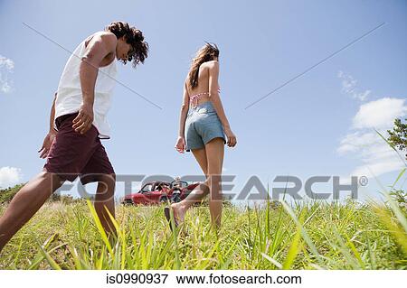 Young couple walking through grass View Large Photo Image Stock Photo - Young couple walking through grass. Fotosearch