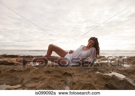 Young woman wearing white top sitting on sand, portrait View Large Photo Image Stock Image - Young woman wearing white top sitting on sand, portrait. Fotosearch