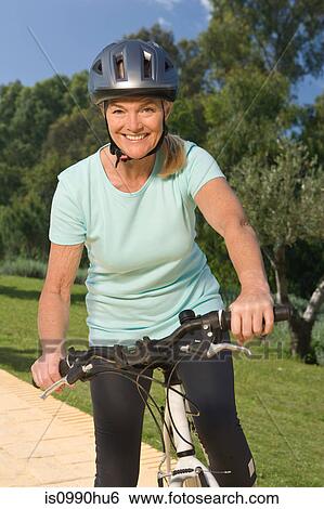 Mature woman cyclist wearing helmet View Large Photo Image Stock Photograph - Mature woman cyclist wearing helmet. Fotosearch