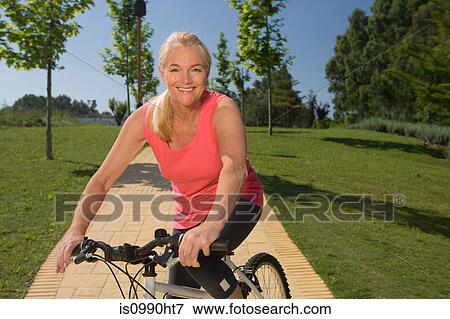 Stock Photo - Mature woman cyclist with bicycle. Fotosearch