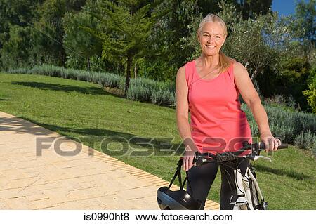 Stock Photo - Mature woman cyclist with bicycle. Fotosearch