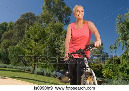 Mature woman cyclist with bicycle View Large Photo Image Stock Photo - Mature woman cyclist with bicycle. Fotosearch