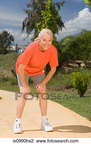 Stock Image - Mature woman runner leaning, catching breath. Fotosearch
