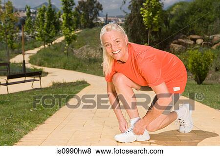 Mature woman runner tying shoelaces View Large Photo Image Stock Photo - Mature woman runner tying shoelaces. Fotosearch