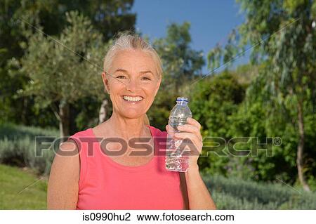 Stock Image - Mature woman runner with bottle of water. Fotosearch