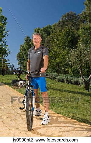 Stock Image - Senior male cyclist with bicycle. Fotosearch