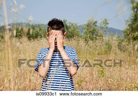 Stock Image - Boy playing hide and seek in field. Fotosearch