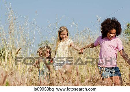 Stock Photography - Friends holding hands in field. Fotosearch