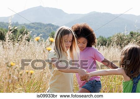 Stock Photography - Friends holding hands in field. Fotosearch