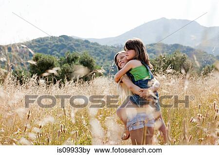Girl carrying friend in field View Large Photo Image Stock Photo - Girl carrying friend in field. Fotosearch