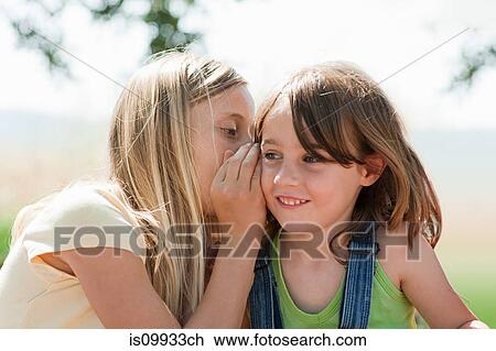 Stock Image - Girl whispering to firiend. Fotosearch