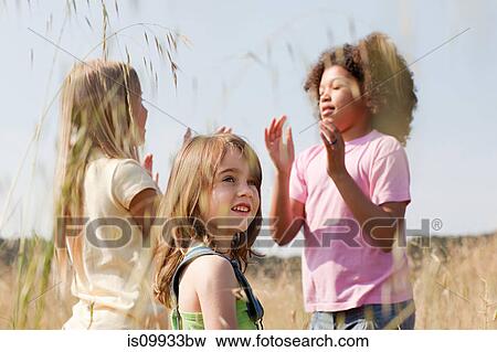 Girls playing pat a cake in field View Large Photo Image Stock Photo - Girls playing pat a cake in field. Fotosearch