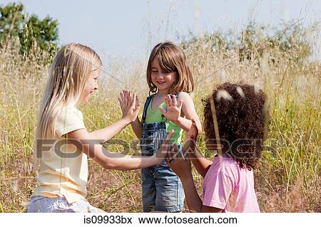 Girls playing pat a cake in field View Large Photo Image Stock Photo - Girls playing pat a cake in field. Fotosearch