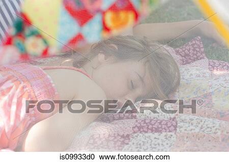 Stock Image - Young girl sleeping in summer netting tent. Fotosearch