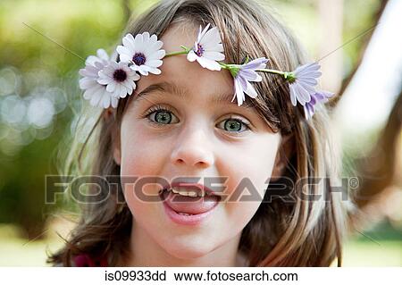 Stock Image - Young girl with daisy chain on head, portrait. Fotosearch