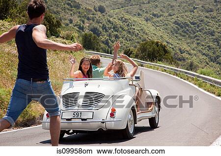 Convertible car driving past hitchhiker View Large Photo Image Picture - Convertible car driving past hitchhiker. Fotosearch