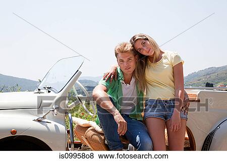 Young couple by convertible car looking at camera View Large Photo Image Stock Photo - Young couple by convertible car looking at camera. Fotosearch