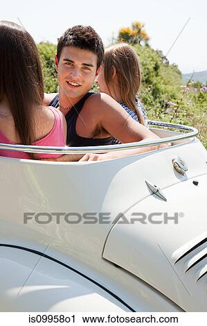 Stock Image - Young friends in convertible car. Fotosearch