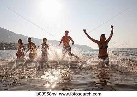 Stock Photo - Young friends splashing in the sea. Fotosearch